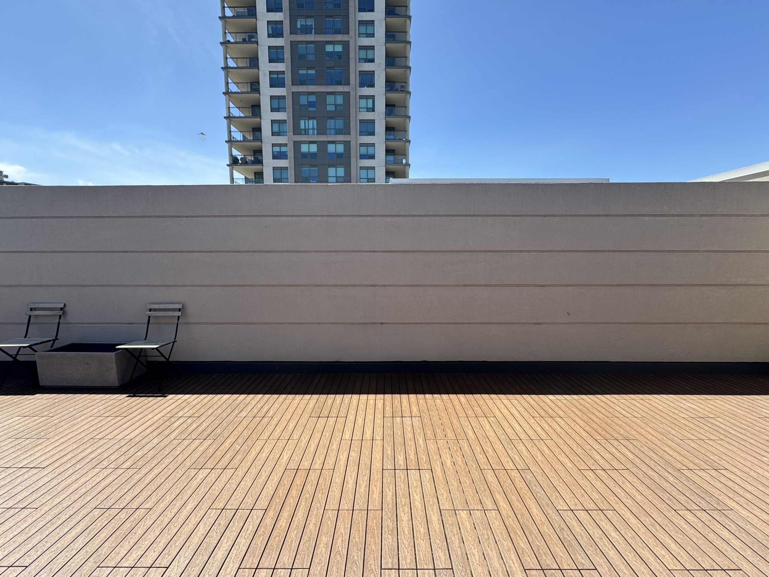 Teak 1x2 WPC deck tiles installed in a staggered pattern on a rooftop terrace of a townhouse in Ajax, complete with deck lights