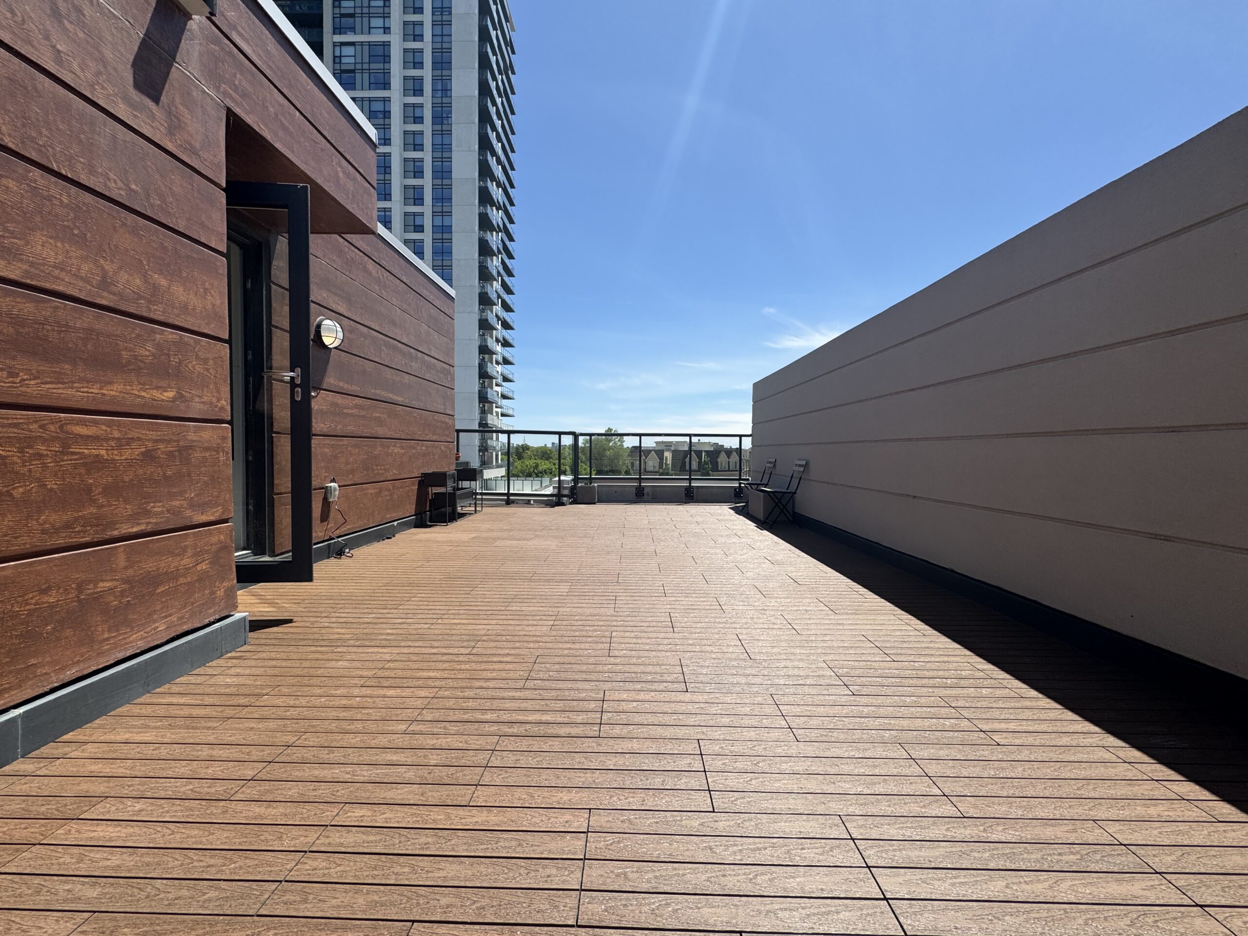 Teak 1x2 WPC deck tiles installed in a staggered pattern on a rooftop terrace of a townhouse in Ajax, complete with deck lights